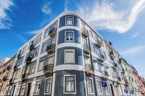 A multi-story building with balconies, a corner entrance, and a clear blue sky. - Saldanha Charm Hideaway (Lisbon)