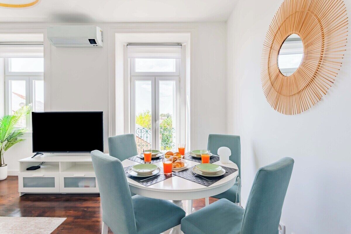 A dining area with a round table, chairs, a television, and a decorative wall piece.