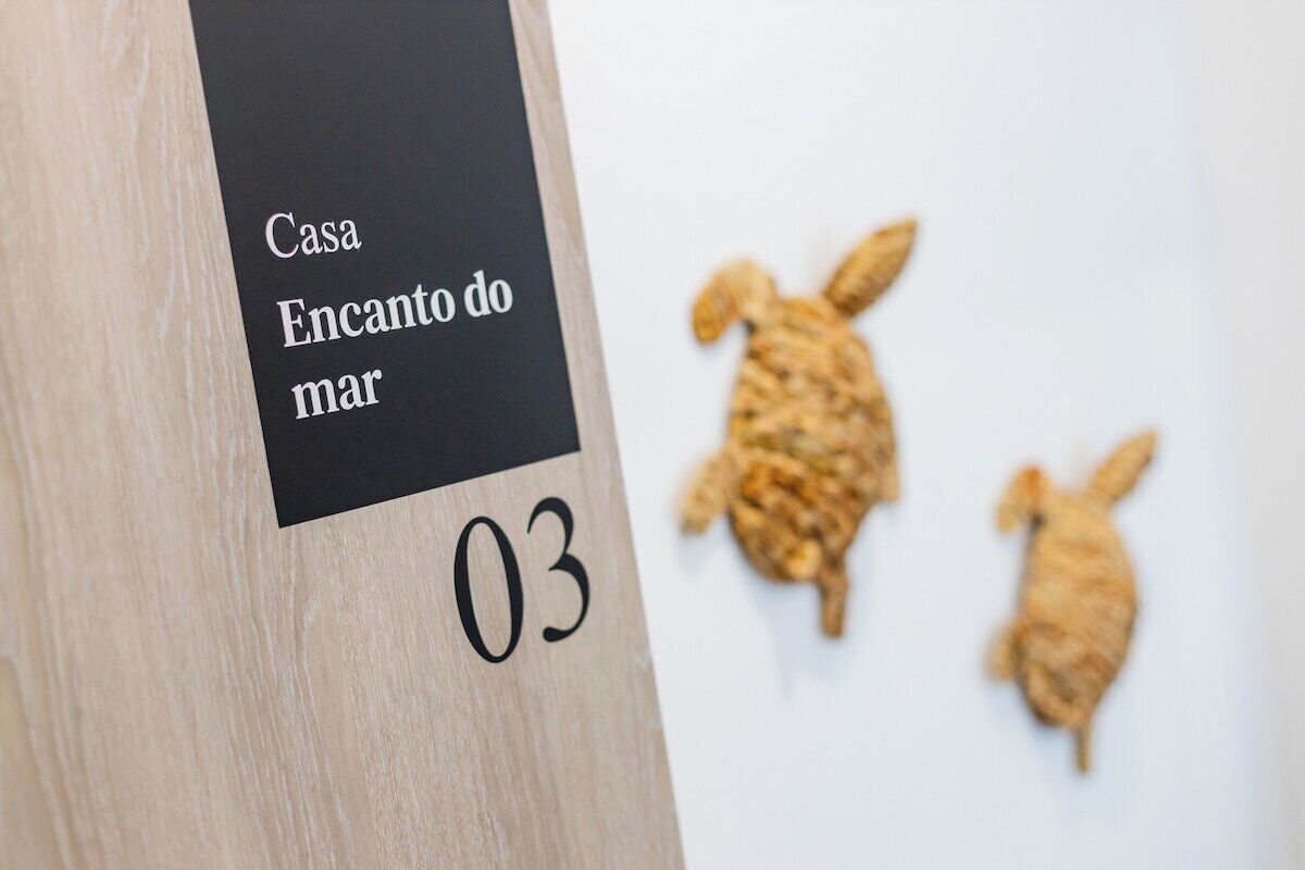 Un cartello di legno con su scritto 'Casa Encanto do mar' e il numero '03', che indica una stanza o un luogo.