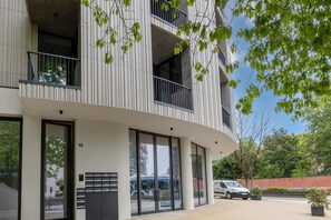 A modern building with a curved facade, large windows, and balconies. - Sage 1BR | Balconies, AC & Parking (Porto)
