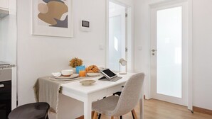 A modern room with a white desk, a laptop, a tablet, and a chair. There is a door with a frosted glass panel and a framed abstract artwork on the wall. - Matosinhos Seaside Comfy Flat (Matosinhos)