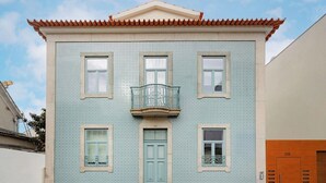 A building with a tiled facade, a central entrance door, and a balcony with a metal railing. - Matosinhos Seaside Comfy Flat (Matosinhos)