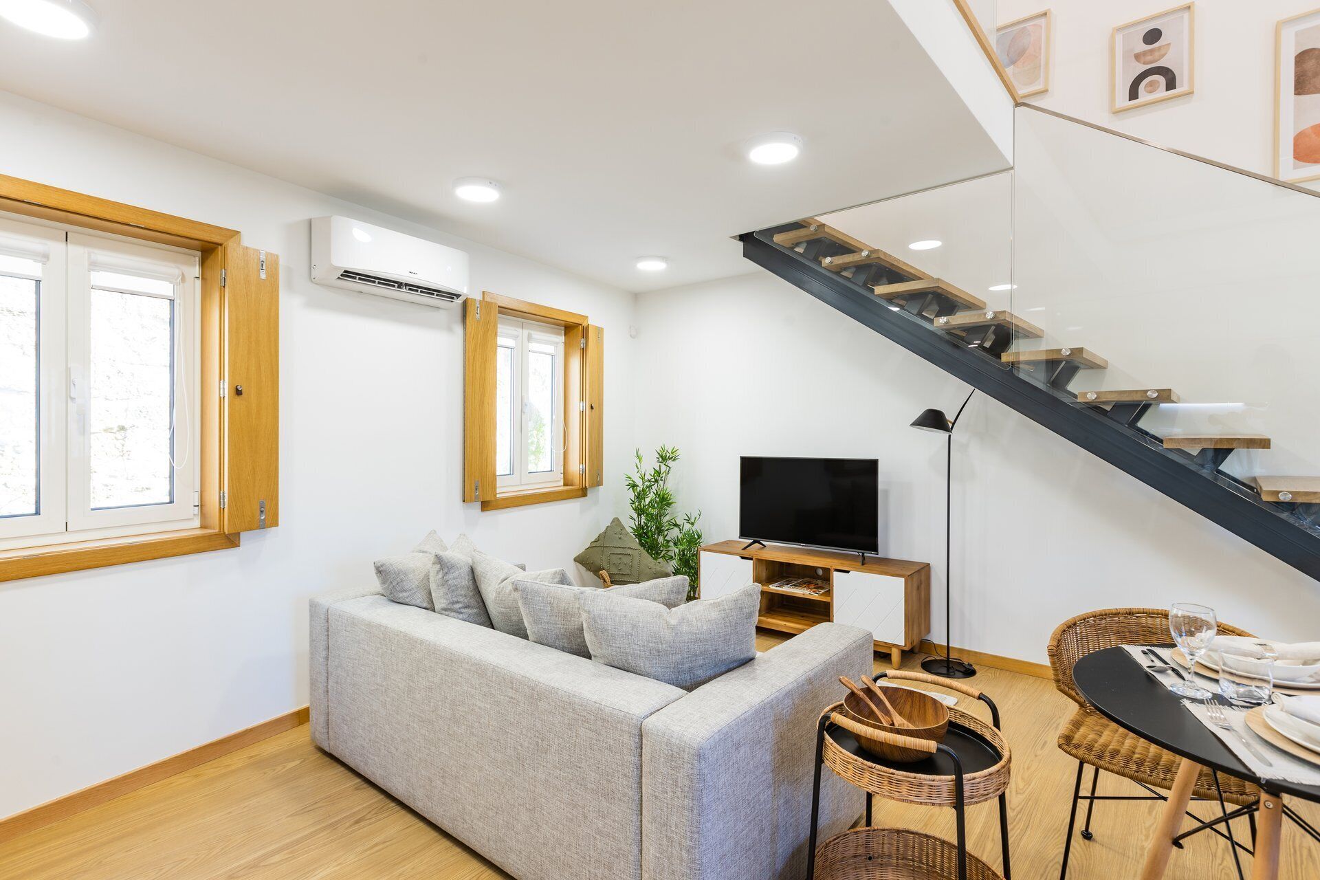 Een moderne woonkamer met een bank, televisie, eettafel en een trap.