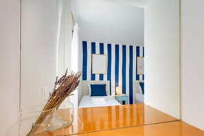 Ein Hotelzimmer mit Bett, Nachttischen, einer Ablage und einer Vase mit Trockenblumen.