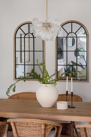 A dining table with a white vase, two candles, and a hanging light fixture. - Carcavelos Terrace & Beach Apartment (Carcavelos)