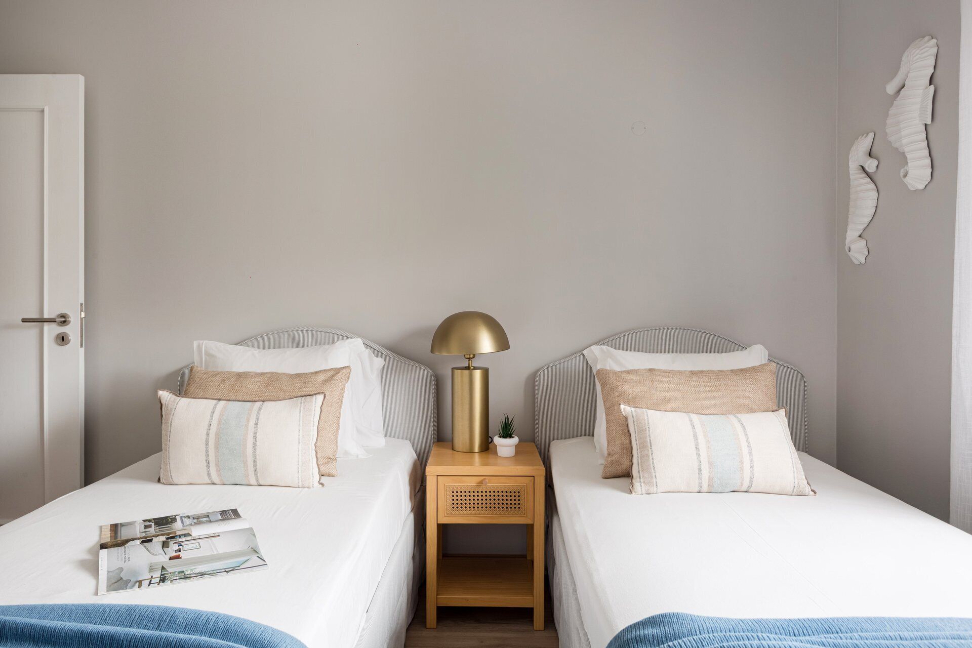 Ein Doppelzimmer mit zwei Betten, einem Nachttisch mit Lampe und einer Zeitschrift auf dem Bett links.