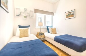 Ein Schlafzimmer mit zwei Betten, einem Fenster, einer Lampe und Wanddekorationen.
