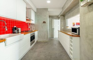 Eine Küche mit weißen Schränken, einer roten Spritzschutzwand und einer Mikrowelle.
