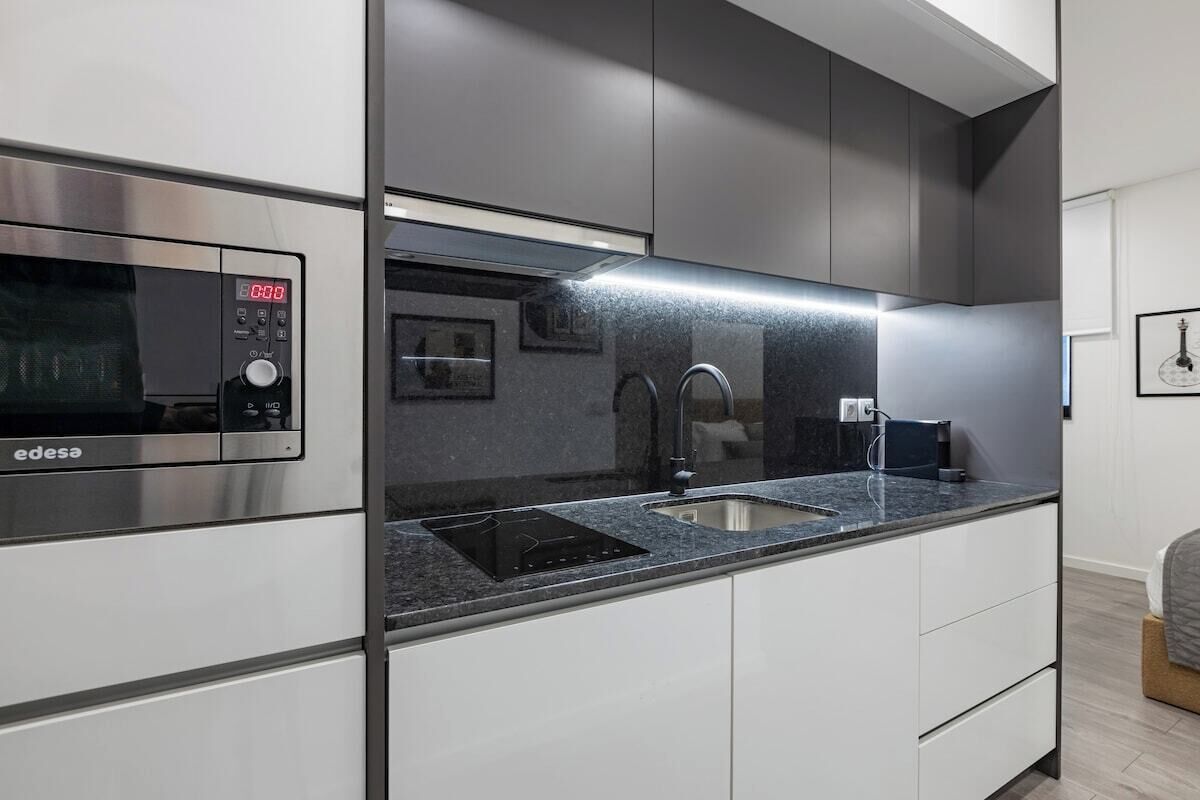 A modern kitchen with a built-in microwave, a stainless steel range hood, and a granite countertop.
