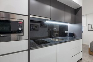 Una cocina moderna con microondas integrado, extractor de acero inoxidable y encimera de granito.