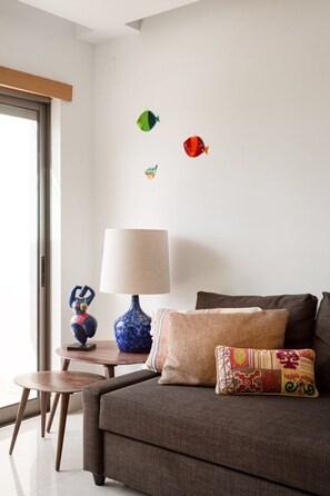 A modern living room with a sofa, a lamp, a small table, and decorative wall stickers. - Albufeira Poolside Family Vila (Albufeira)