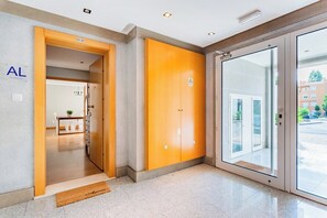 Un hall d’hôtel avec un comptoir d’accueil, une porte en bois avec une enseigne et une porte vitrée donnant sur l’extérieur.