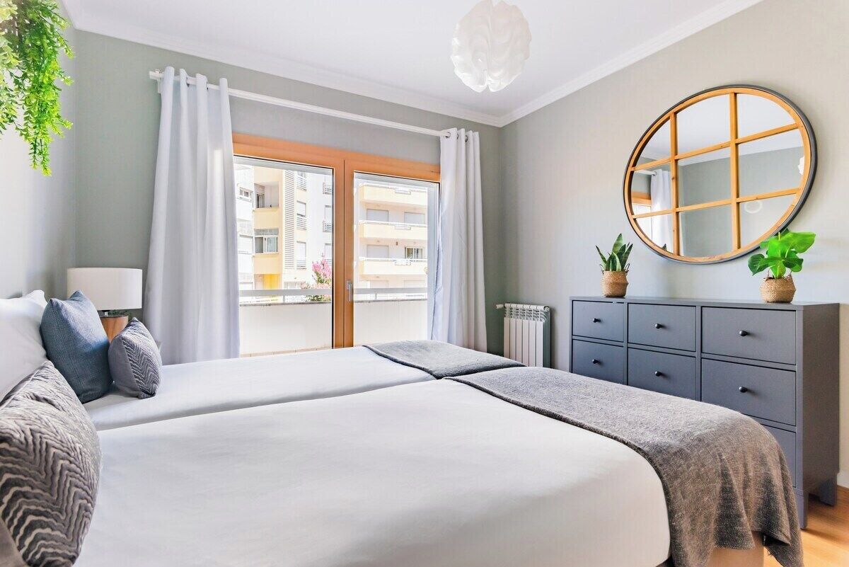 Et hotelværelse med seng, kommode, spejl og udsigt ud