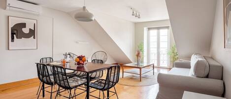 A modern living room with a dining area, a sofa, and a dining table with chairs.
