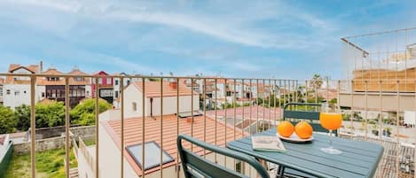 A balcony with a table, two chairs, a book, and two glasses of orange juice.