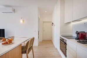 A modern kitchen with a dining area, white cabinetry, a built-in oven, and a coffee machine. - The Bright Life @ BoaVista Flats (Porto)