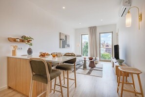 A modern kitchen with a dining area, a TV, and a large window with curtains. - The Bright Life @ BoaVista Flats (Porto)