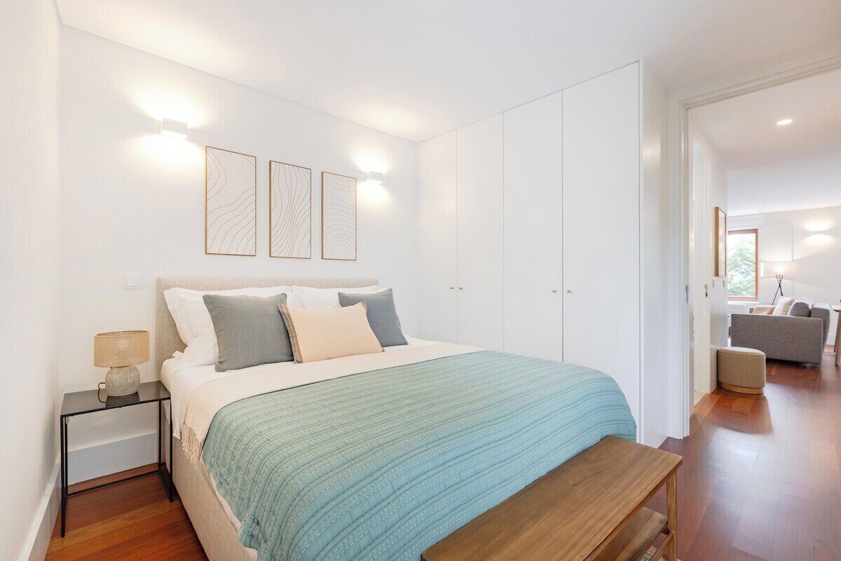 Een slaapkamer met een bed, nachtkastje en wandlampen.