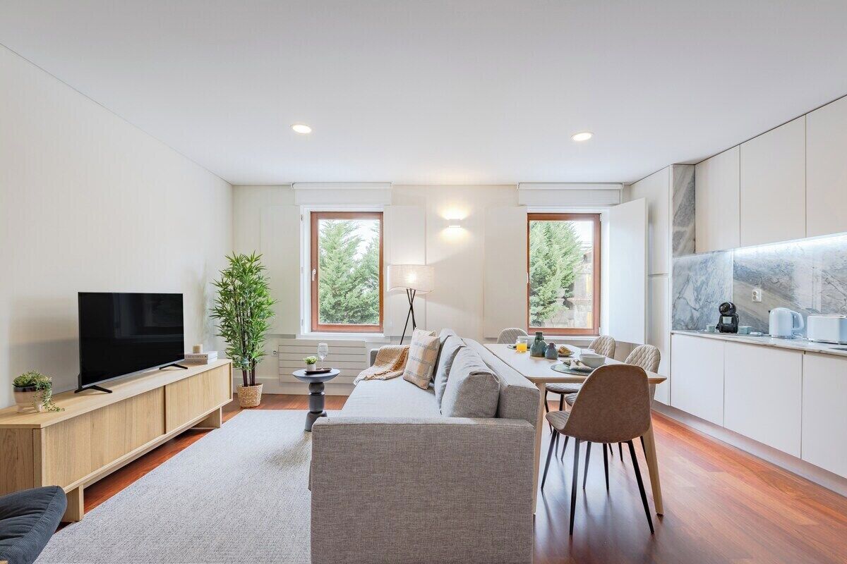 A modern living room with a sofa, TV, and dining area.
