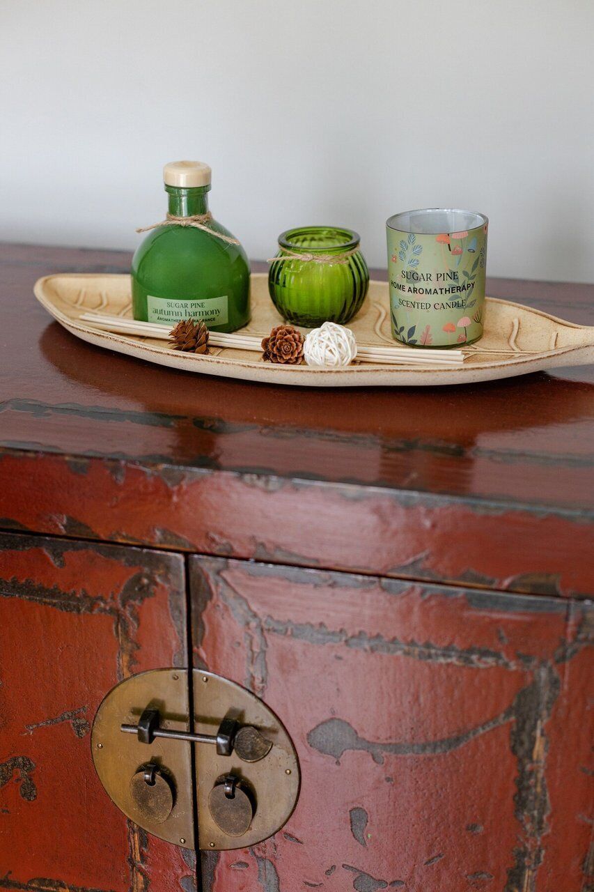 Ein Holzkabinet mit rustikalem Design, eine Ablage mit einer grünen Flasche, einem grünen Einmachglas und einer Duftkerze.
