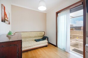 A room with a sofa, a wooden cabinet, a ceiling light, and a sliding glass door leading to an outdoor area. - Espinho Retreat with Balcony (Espinho)
