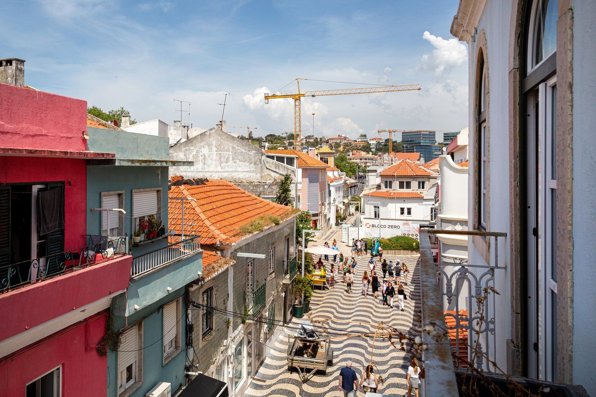 Una calle estrecha flanqueada por edificios, una grúa de construcción y personas caminando.