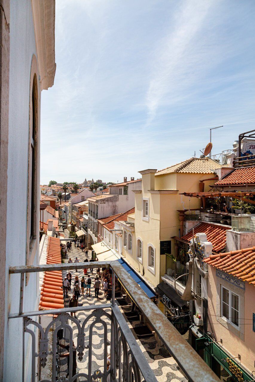 A narrow street with buildings on both sides, a staircase, and a clear sky.