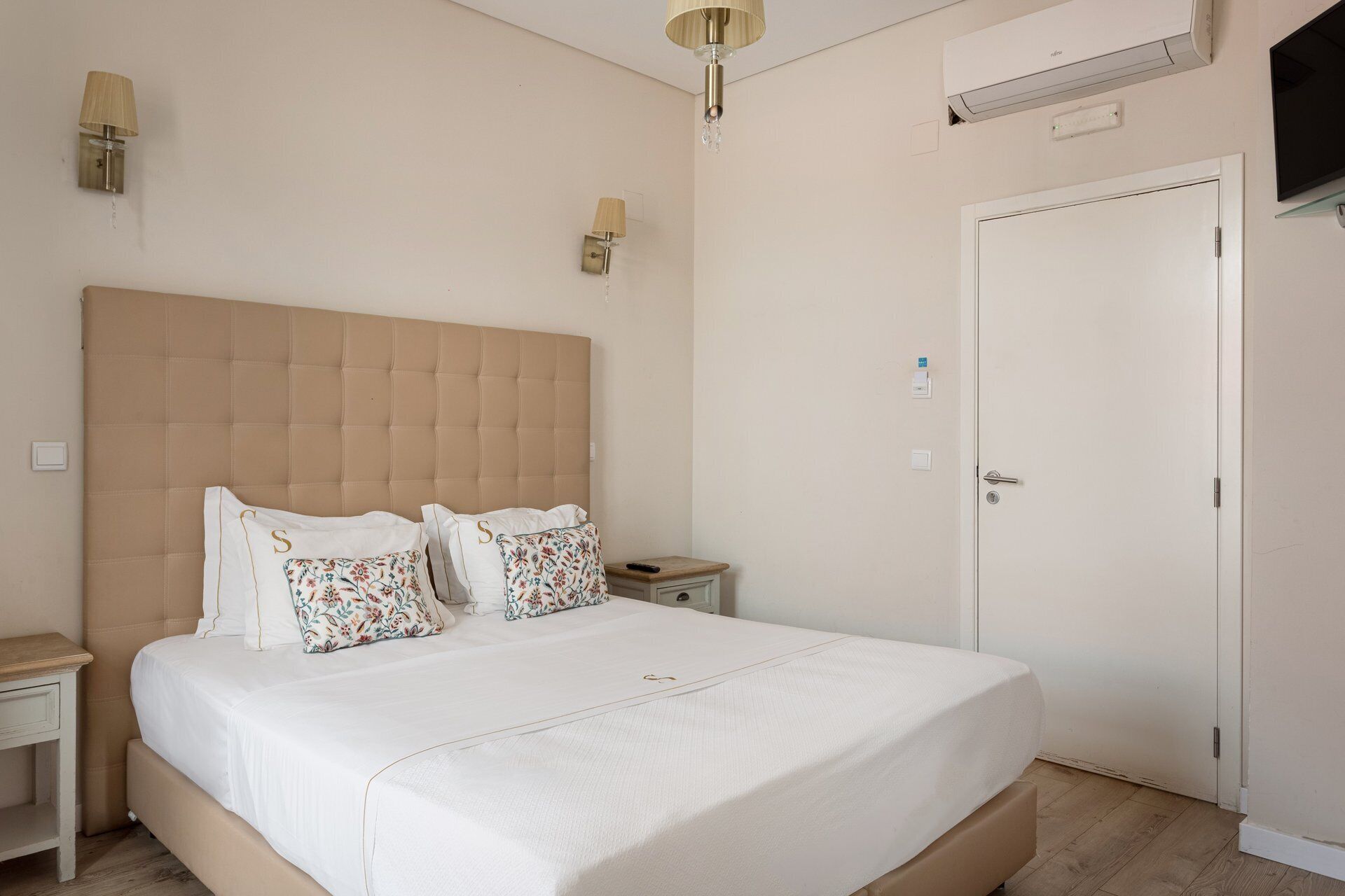 Camera da letto con un letto grande, due comodini, un tavolino e un condizionatore d'aria a parete, oltre a una porta.