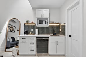 A modern kitchen with white cabinetry, a microwave, a dishwasher, and a built-in oven.