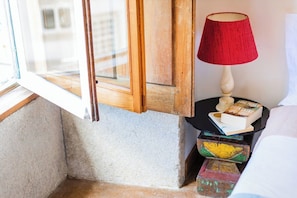 A corner of a room with a wooden door, a red lamp, a small table with a book and a candle, and colorful boxes. - Rosarinho Cruz invites to her Atelier by the River (Porto)