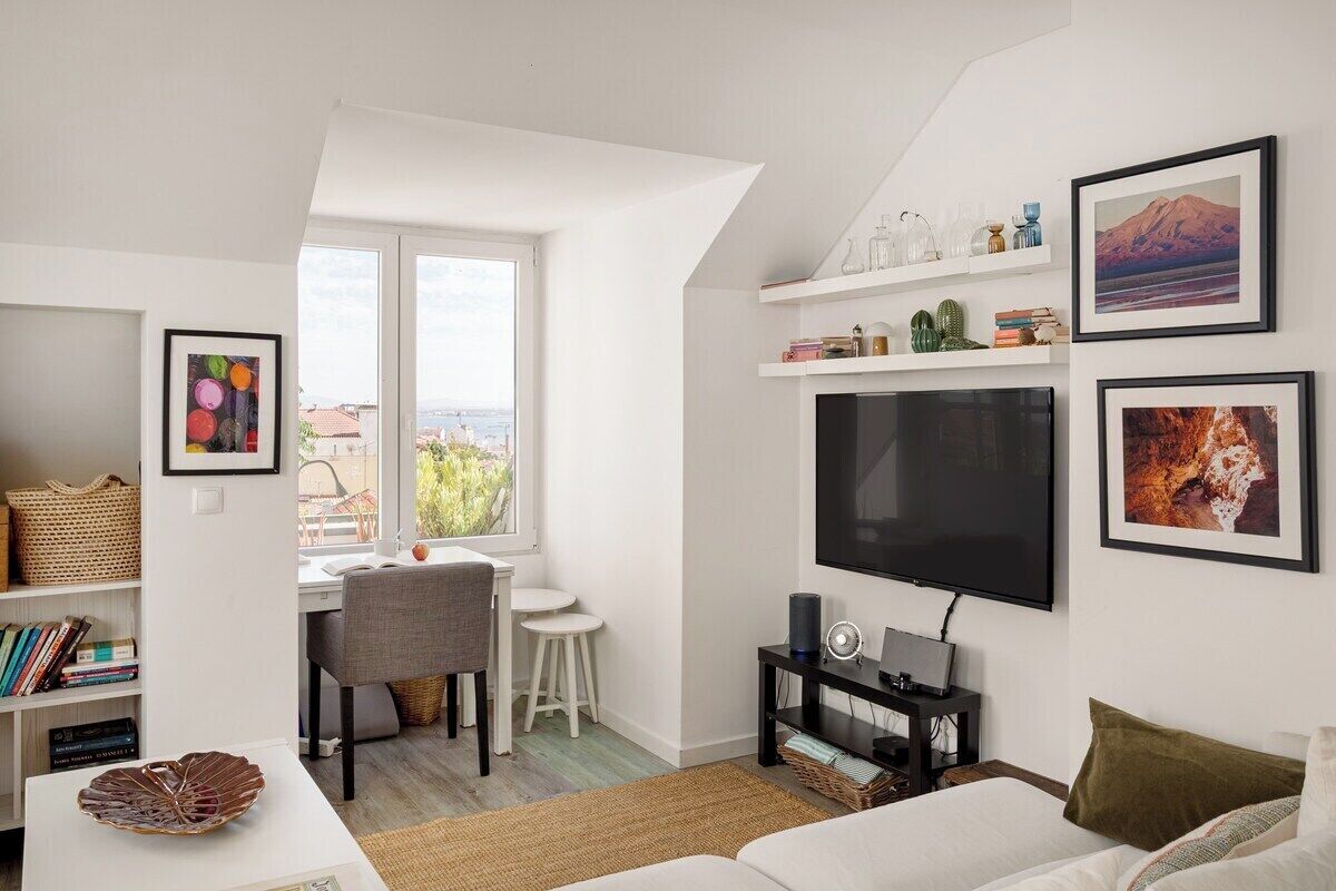 Una sala moderna con televisor de pantalla plana, un comedor con mesa y sillas, y una estantería.
