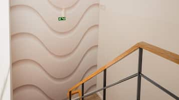 Una escalera con diseño moderno, un tragaluz y una señal de salida de emergencia verde.