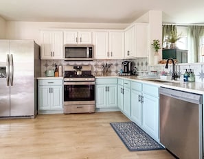 Een keuken met witte kastjes, roestvrijstalen apparatuur en een blauw aanrecht.