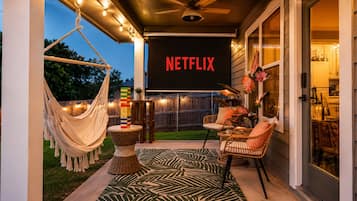 An outdoor patio area with a hammock, wicker furniture, and a Netflix sign.