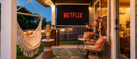 Eine Außenpatio-Terrasse mit einer Hängematte, Korbmöbeln und einem Netflix-Schild.