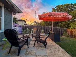 Een terras met buitenmeubilair, een rode parasol en een houten omheining.