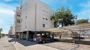 Een modern gebouw met een overdekte parkeerplaats en een auto ervoor.