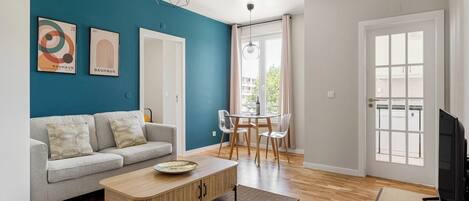 Un salon moderne avec un mur d’accent bleu, un canapé, une table basse et un téléviseur.