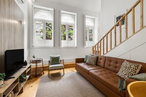 A living room with a TV, a sofa, a chair, and a staircase. - Porto Garden | Mezzanine Loft (Porto)