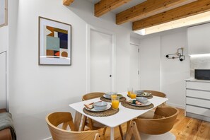 A dining area with a white table, wooden chairs, and a breakfast setting. - Porto Garden | Mezzanine Loft (Porto)