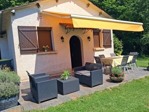 Ein Gebäude mit einer Terrassenfläche, ausgestattet mit Korbmöbeln, einem Tisch und Stühlen.