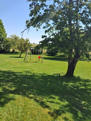 Ein grüner Park mit Schaukeln und einem Baum.