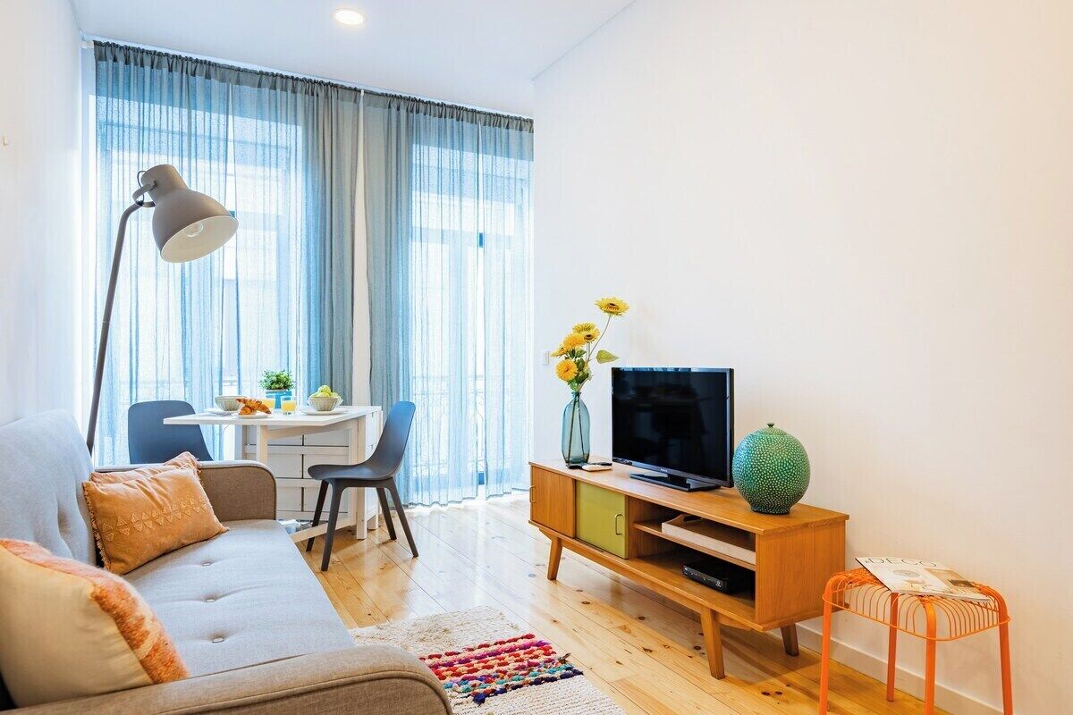 Ein modernes Wohnzimmer mit einer Couch, einem Fernseher und einem Essbereich mit Tisch und Stühlen.