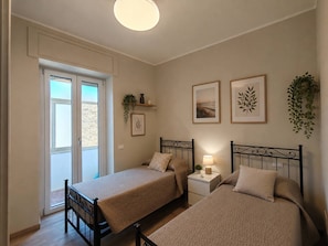A bedroom with two beds, a window, and a door.