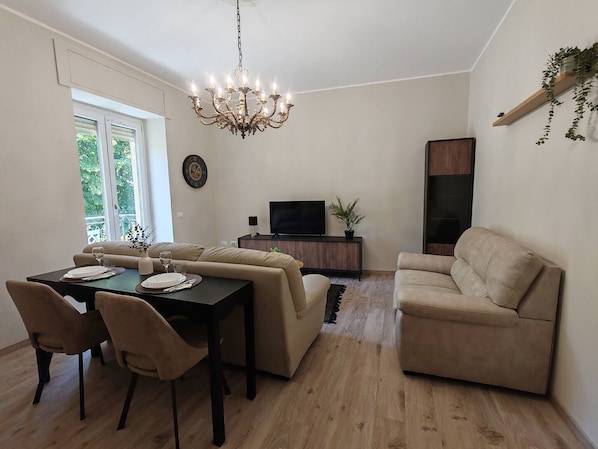 A living room with a dining area, a chandelier, a TV, and a sofa.