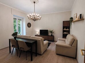 A modern living room with a sofa set, a dining table with chairs, a TV, and a bookshelf.