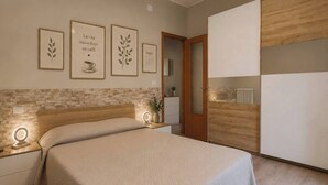 A bedroom with a bed, bedside tables, a wardrobe, and wall art. - Cozy Apartment Overlooking the Main Square (Orsogna)