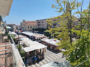 A bustling outdoor market with multiple stalls and a pedestrian crossing.