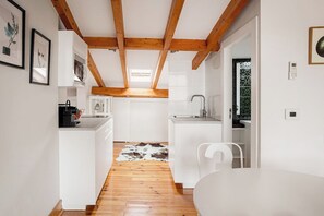 A modern kitchen with white cabinetry, a wooden ceiling, and a cowhide rug on the floor. - Arriaga River Views II (Lisbon)