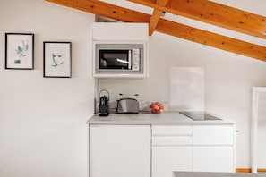 A compact kitchen with a microwave, toaster, and a bowl of apples on the counter. - Arriaga River Views II (Lisbon)